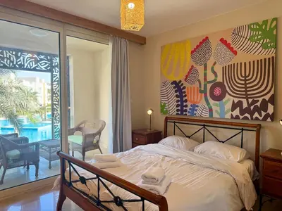 a bedroom with a bed and a painting on the wall at Cozy 2BR Plus Nanny - Free Beach&Pool In Mangroovy ElGouna in Hurghada
