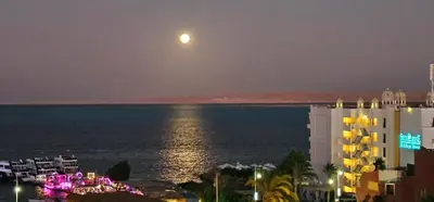 a full moon over the ocean at night at ROOF TOP 12 Seaview in Hurghada