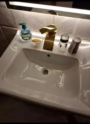 a white bathroom sink with a gold bow on it at Villa Azad Elkber in Quseir