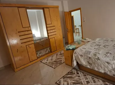 a bedroom with a bed and a large wooden cabinet at Villa Azad Elkber in Quseir