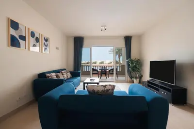 a living room with two blue couches and a television at Joubal 2BR Lagoon View Residence in Hurghada