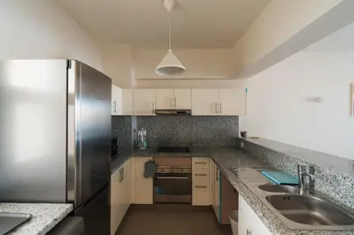 a kitchen with white cabinets and a stainless steel refrigerator at Joubal 2BR Lagoon View Residence in Hurghada