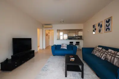 a living room with a blue couch and a tv at Joubal 2BR Lagoon View Residence in Hurghada
