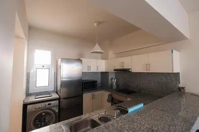 a kitchen with a stainless steel refrigerator and a sink at Joubal 2BR Lagoon View Residence in Hurghada