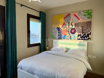 a bedroom with a white bed with a painting on the wall at Sunny 4BR Villa Plus Nanny With Private Heated Pool And Jacuzzi In ElGouna in Hurghada