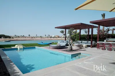 a swimming pool with a table and chairs and an umbrella at BYTK - La Serena in Hurghada