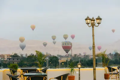 a bunch of hot air balloons flying in the sky at The View Luxor hotel in Luxor
