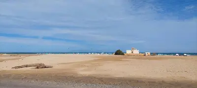 a sandy beach with a building in the distance at Relax near the sea, one bedroom flat in Hurghada