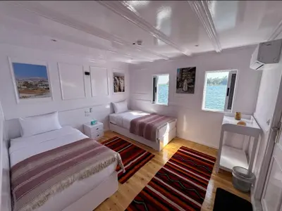 a bedroom with two beds and a couch in it at Soul of the nile Dahabyia in Al Baghdādī