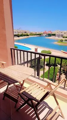 a wooden bench sitting on a balcony with a view of a river at Hayloft 1 bedroom tawila, Plaza ElGouna in Hurghada