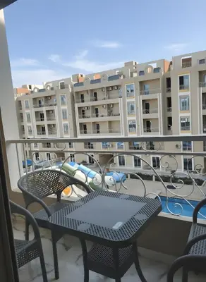 a balcony with tables and chairs in front of a building at HUB resort Luxury apartment on the pool in Hurghada