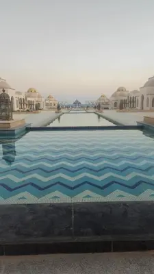 a large swimming pool with blue tiles on the ground at Paradise Studio with pool in Hurghada