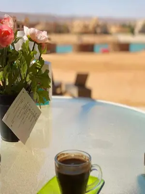 a table with a cup of coffee and a vase of flowers at El Gouna - Sabina - Lagoon Chalet - 2 bedrooms - Ground Floor in El Gouna