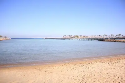 a sandy beach with a pier in the water at Scandic resort near diving center Colona Divers Hotel Room in Hurghada