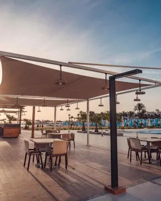 a group of tables and chairs under an umbrella at Scandic resort near diving center Colona Divers Hotel Room in Hurghada