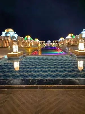 a fountain in the middle of a city at night at Beachfront luxury Palm Beach Piazza Private Beach in Hurghada