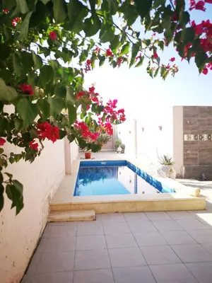 a swimming pool in a courtyard with red flowers at Villa malaika with Private swimming pool in Luxor