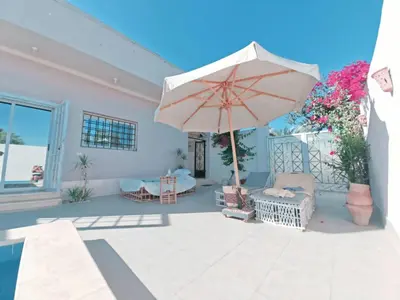 a patio with an umbrella and chairs and a couch at Villa malaika with Private swimming pool in Luxor