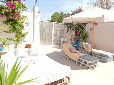 a patio with chairs and an umbrella and flowers at Villa malaika with Private swimming pool in Luxor