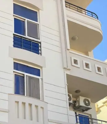 a white building with blue windows and a balcony at apartment 20 in Hurghada
