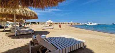 a beach with chairs and umbrellas and the ocean at Princess Resort Hurghada in Hurghada