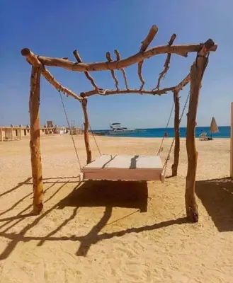 a swing on a beach with the ocean in the background at Princess Resort Hurghada in Hurghada