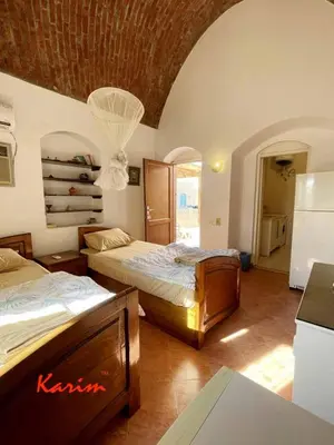a room with two beds and a kitchen with a refrigerator at Studio For Rent in El Gouna Kafr in Hurghada