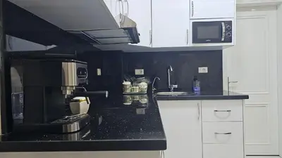 a kitchen with white cabinets and a black counter top at Apartment 95sqm with sea view in Hurghada