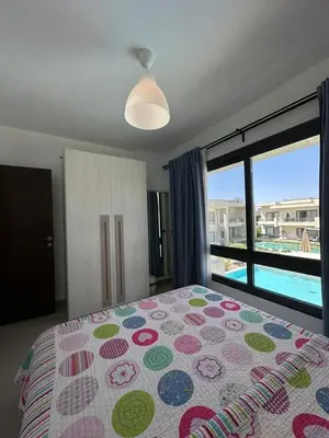 a bedroom with a bed and a view of a pool at Refined Two-Bedroom with Pool View Gcribs ElGouna in El Gouna