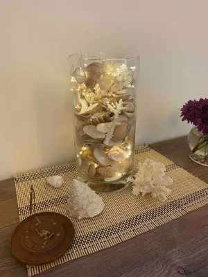a glass vase filled with shells and lights on a table at One bedroom apartment with stunning sea view in Hurghada