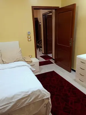 a bedroom with a bed and an open door at Lutos flower apartment 2 in Al Karnak