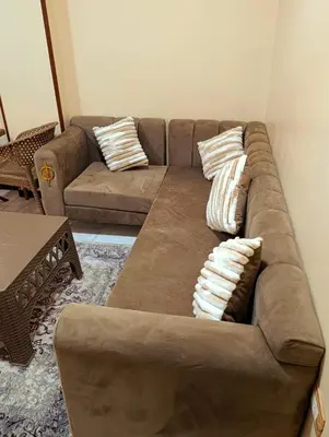 a brown couch with pillows in a living room at Lutos flower apartment 2 in Al Karnak