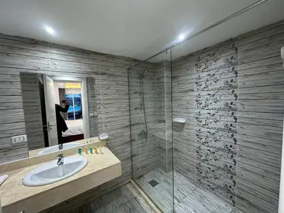 a bathroom with a sink and a glass shower at Elegant 3BR Luxury Suite - Fanadir Bay in Hurghada