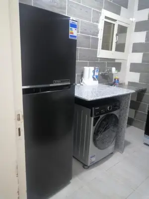 a black refrigerator in a kitchen with a washing machine at بيت الاستجمام in Idfū