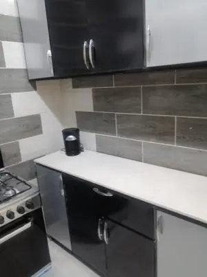 a kitchen with black cabinets and a white counter top at بيت الاستجمام in Idfū
