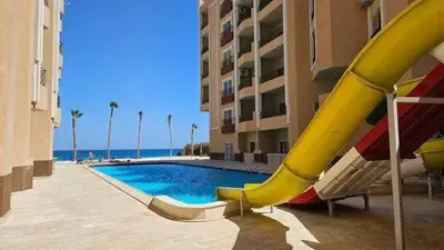 a pool with a slide next to a building at Juliana beach resort in El Gouna