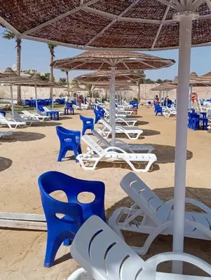 a group of chairs and umbrellas on a beach at Juliana beach resort in El Gouna