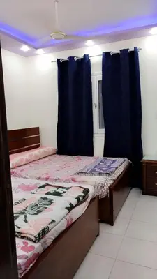 a bedroom with two beds and blue curtains at Apartment in sherry street near sheraton in Hurghada