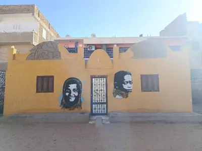 a building with two faces painted on the side of it at Rooma ka Guest House in Aswan