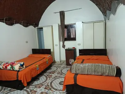 two beds in a room with orange sheets at Rooma ka Guest House in Aswan