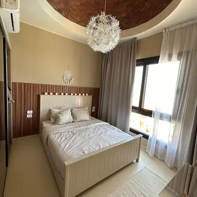 a bedroom with a white bed and a chandelier at Best view in Makadi bay private rooftop PHASE 2 Makadi Heights in Hurghada