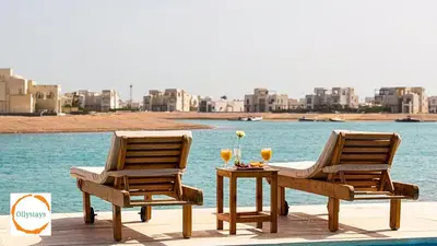 two chairs and a table with wine glasses on a patio at Ancient Sands 4BR Villa Heated pool in El Gouna
