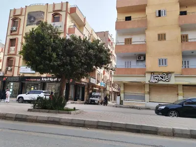 a city street with cars parked in front of buildings at روف كناريا in Luxor