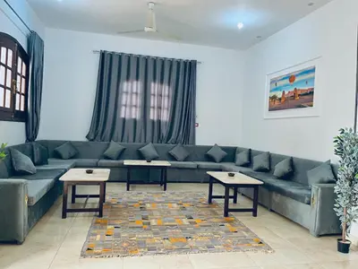 a living room with a green couch and two tables at Farah Hotel in Al Aqālitah