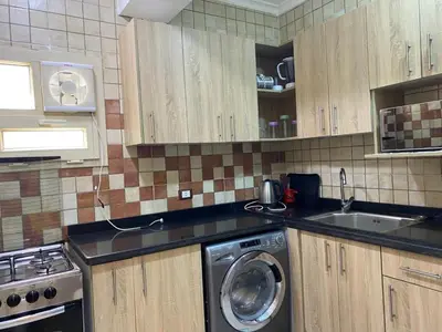a kitchen with wooden cabinets and a washing machine at Star Beach 3BR in Hurghada