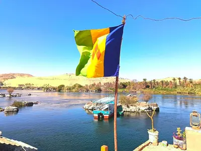 a flag on a river with a boat in the water at Shellaly Ca Nubian Heritage House in Jazīrat Salūjah