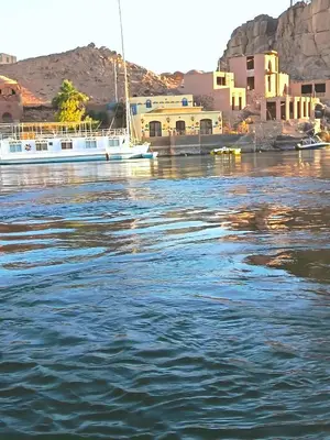 a boat is docked in the water next to a city at Shellaly Ca Nubian Heritage House in Jazīrat Salūjah