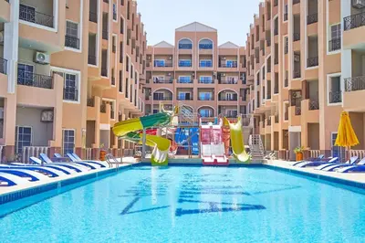 a swimming pool with slides and chairs in a resort at Juliana Beach Resort, Hurghada in Hurghada