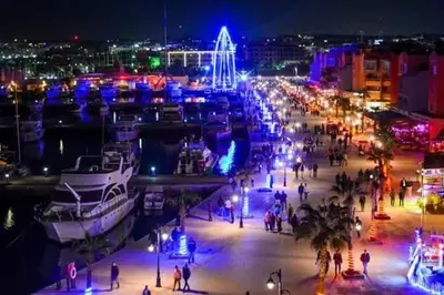 a group of people walking around a harbor at night at عماره المهندس in Hurghada