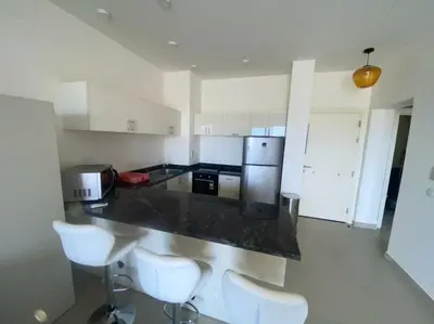 a kitchen with white cabinets and a counter with white chairs at Lovely 1 bd apartment with amazing view in Tawila in Hurghada